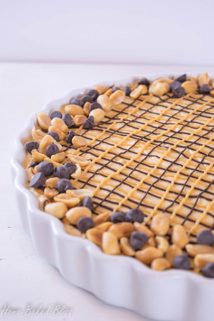 Peanut butter chocolate pie drizzled with chocolate and peanut butter and decorated with chocolate chips and peanuts.