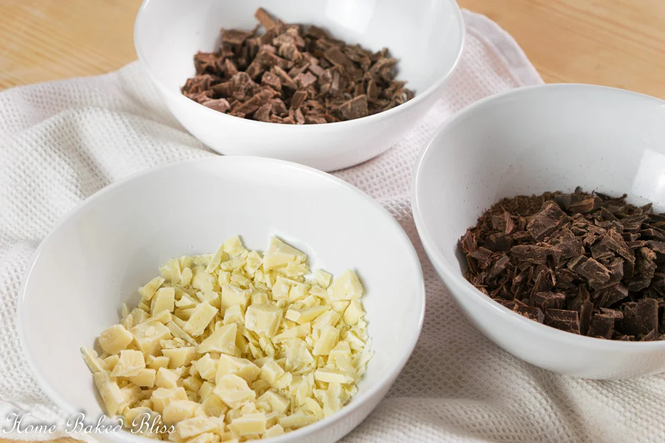 3 bowls with milk chocolate, white chocolate and dark chocolate.o