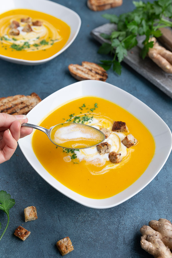 Taking a spoonful of creamy vegan carrot coconut soup