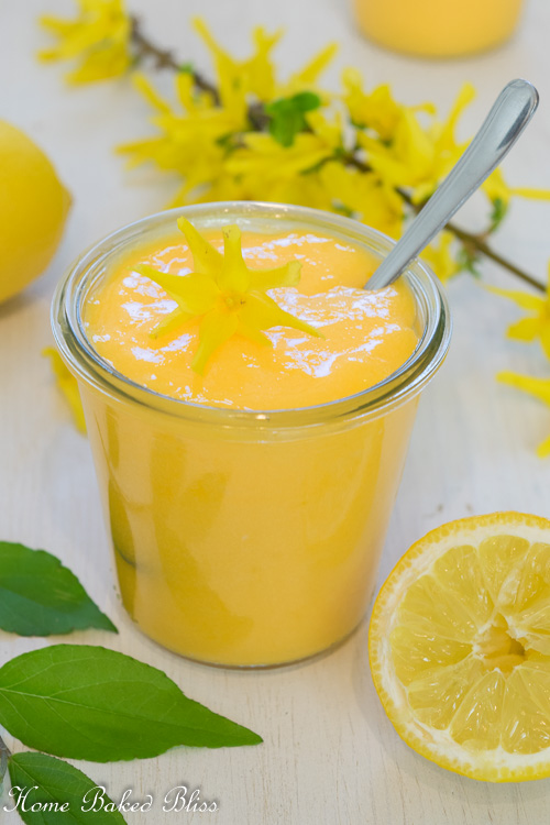 Fresh lemon curd in a glass jar garnished with a flower.
