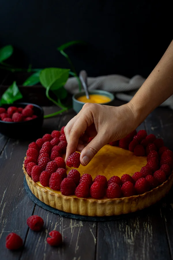 Placing fresh raspberries on a layer of lemon curd