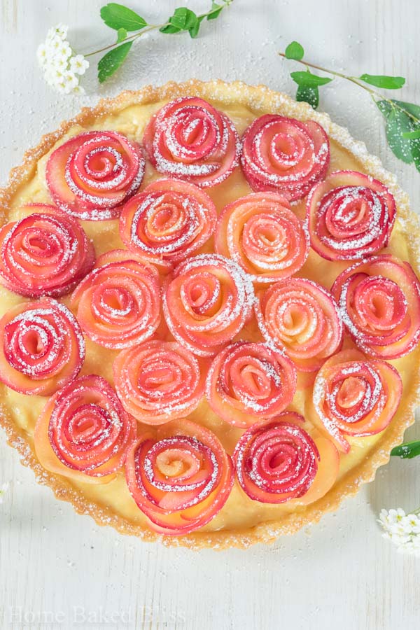 Apple rose tart dusted with powdered sugar and garnished with flowers