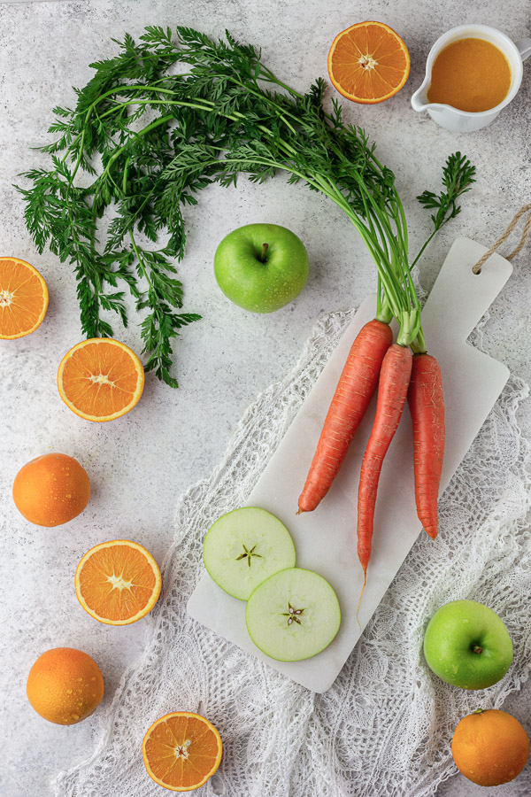 Fresh carrots, apples and oranges on a white background