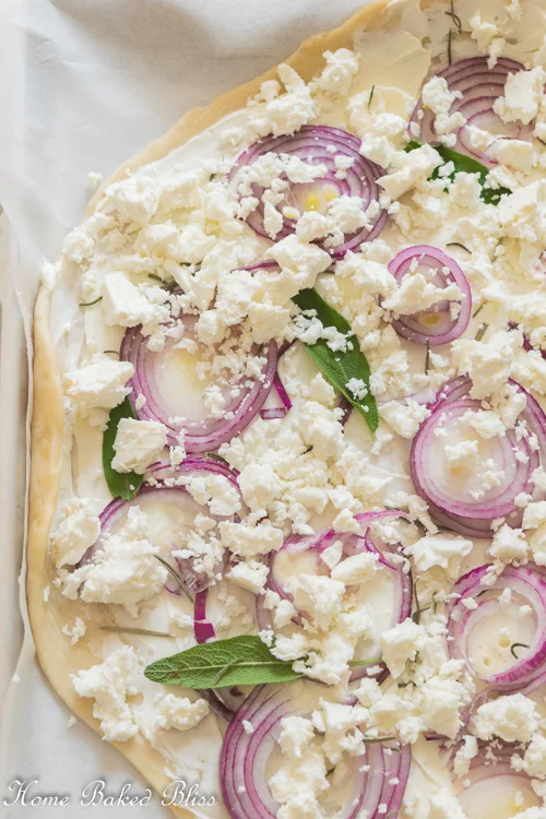 Unbaked Tarte Flambée with onions, feta and fresh herbs