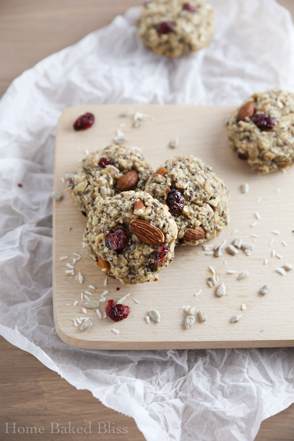 Three breakfast cookies with cranberries and coconut on a wooden board.