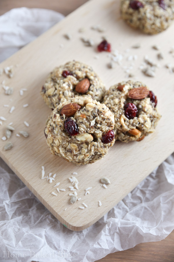 Three breakfast cookies with cranberries and coconut on a wooden board.