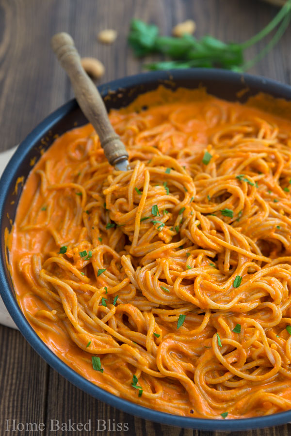 Thick and creamy roasted red bell pepper sauce with noodles in a pan.