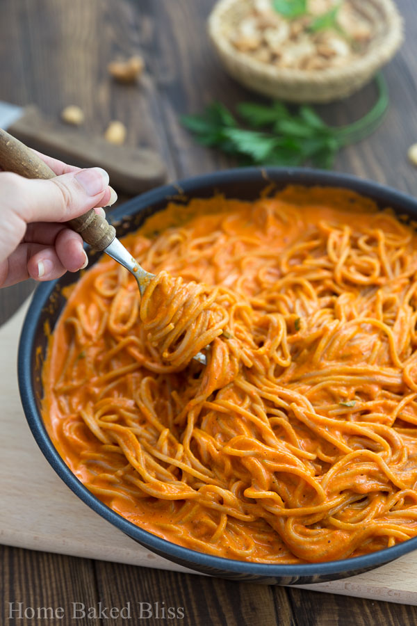 A fork digging into the thick and creamy roasted red bell pepper sauce with noodles.