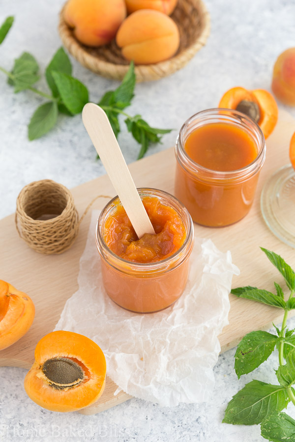 A wooden spoon inside a jar of homemade apricot jam.