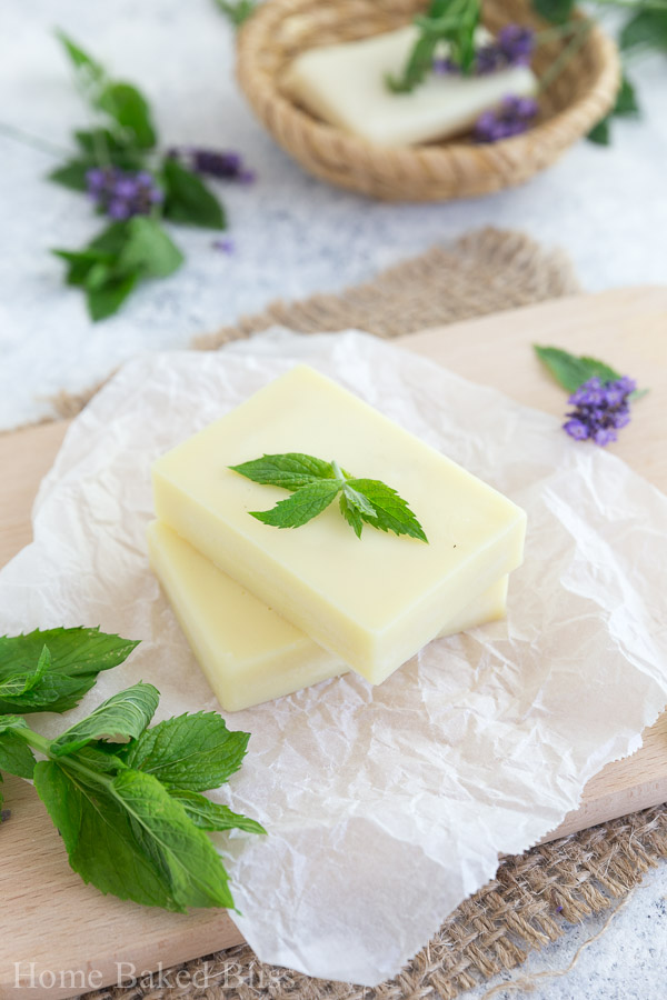 A closeup of the peppermint lotion bars on a wooden board decorated with fresh mint leaves