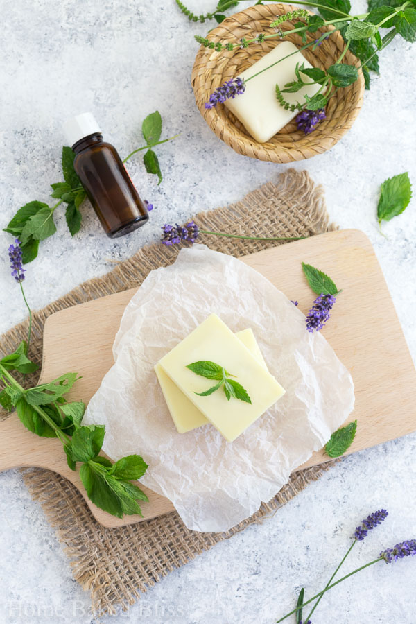 Peppermint Lotion Bars on a wooden board beside fresh mint and lavender.