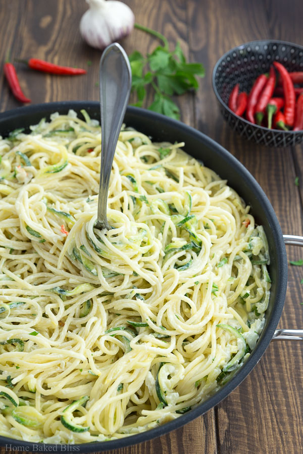 A fork stuck inside a pan of creamy zucchini noodles.