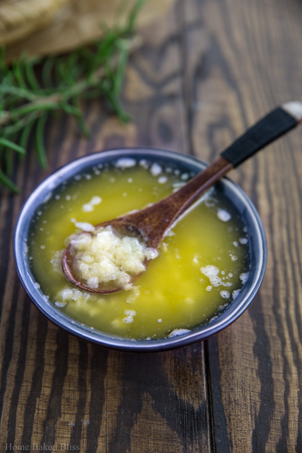 Garlic butter in a small blue dish with a wooden spoon.