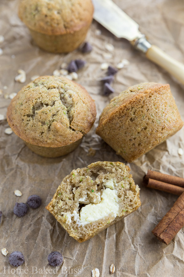 A closeup of the zucchini muffins filled with cream cheese on brown parchment paper.