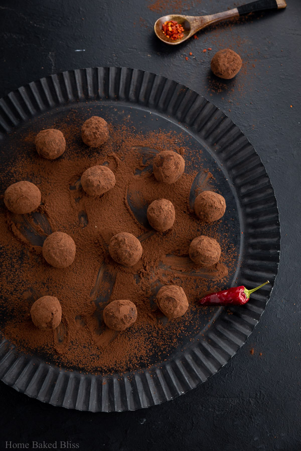 Spicy chili truffles rolled in cocoa powder on a black plate.