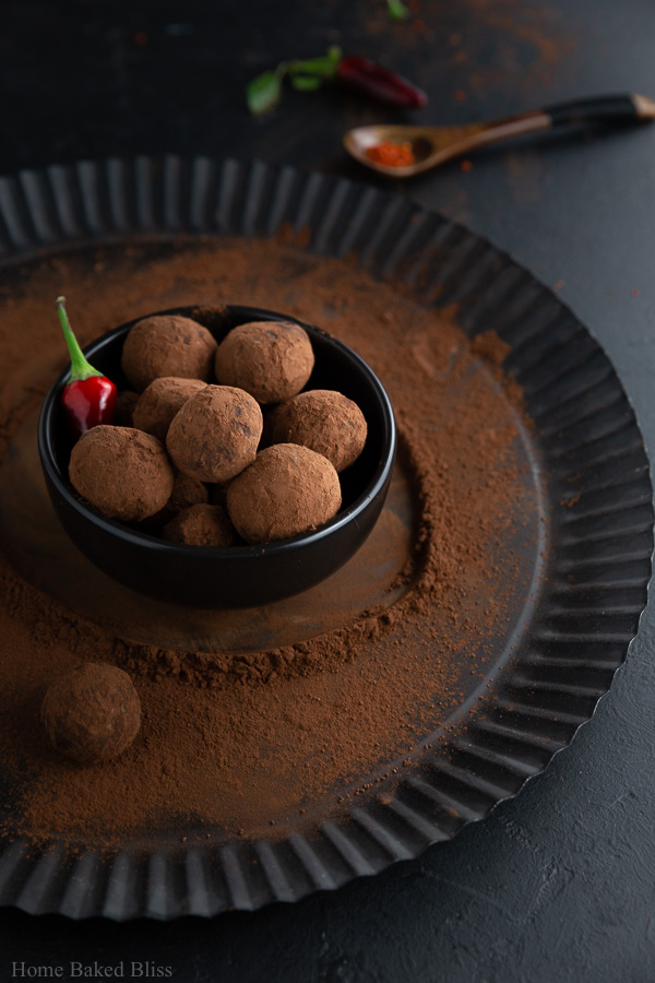 Spicy chili truffles inside a dark brown bowl.