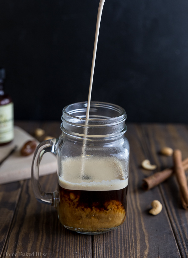 Cinnamon cashew milk creamer being poured into a mason jar filled with coffee.