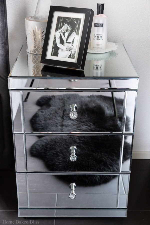 A mirror nightstand with a picture frame on top.