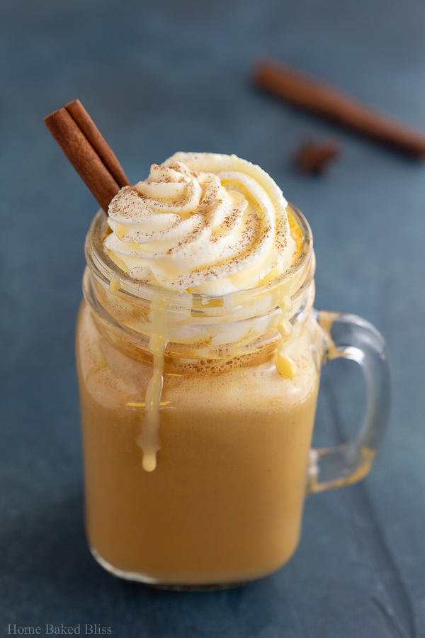 A pumpkin spice latte garnished with whipped cream and a cinnamon stick.