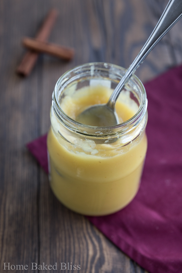 A jar of apple sauce with a spoon inside.