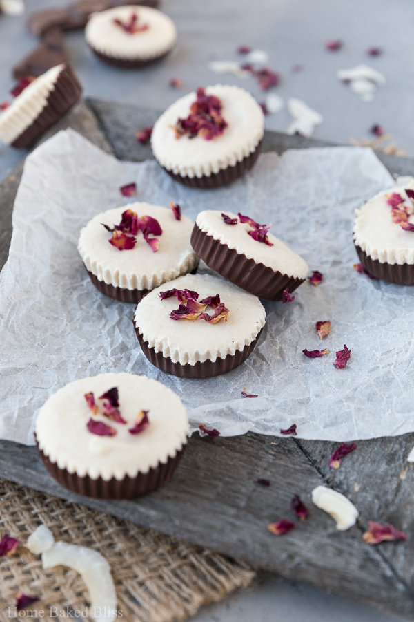 Vegan rose infused chocolate cups on white parchment paper garnished with rose petals.