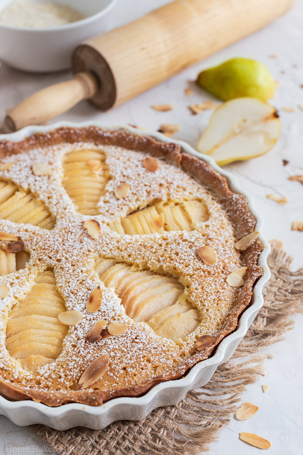 Closeup of Pear Frangipane Tart sprinkled with powdered sugar and garnished with toasted sliced almonds