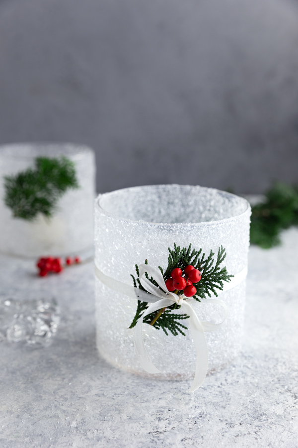 DIY frosted candle jar with epsom salt, decorated with holly and white ribbon