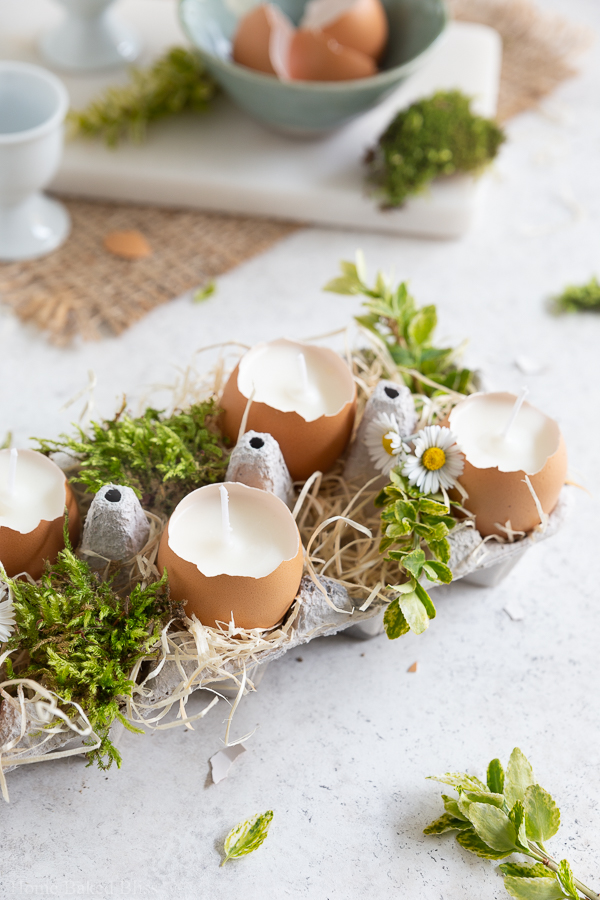 Closeup of the Easter candles in an egg carton decorated with wood shavings and greenery