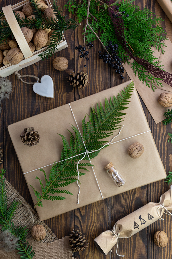 A large gift wrapped in brown paper decorated with a fern leaf