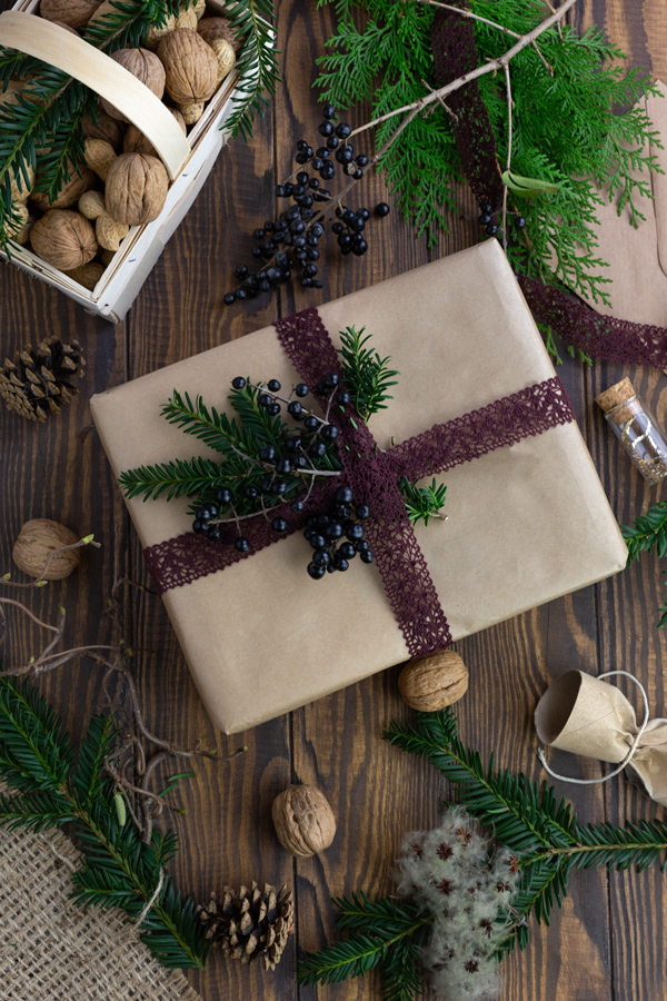 A large gift wrapped in brown paper and decorated with blue holly