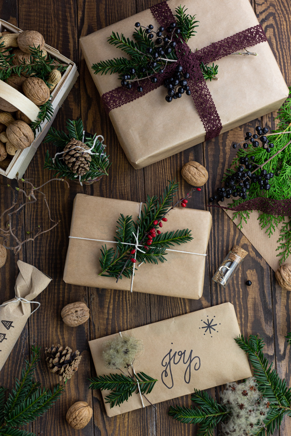 Various gifts wrapped in brown paper and decorated with greenery