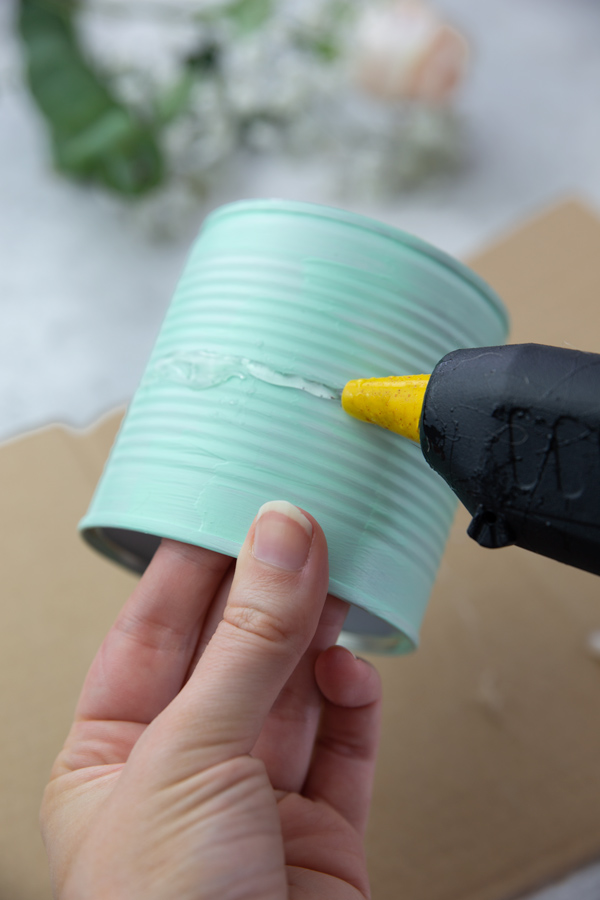 Hot glueing a strip of fabric to the DIY flower pots