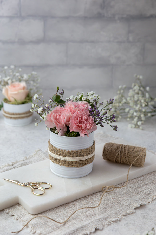 An upcycled white painted tin can with pink and white flowers