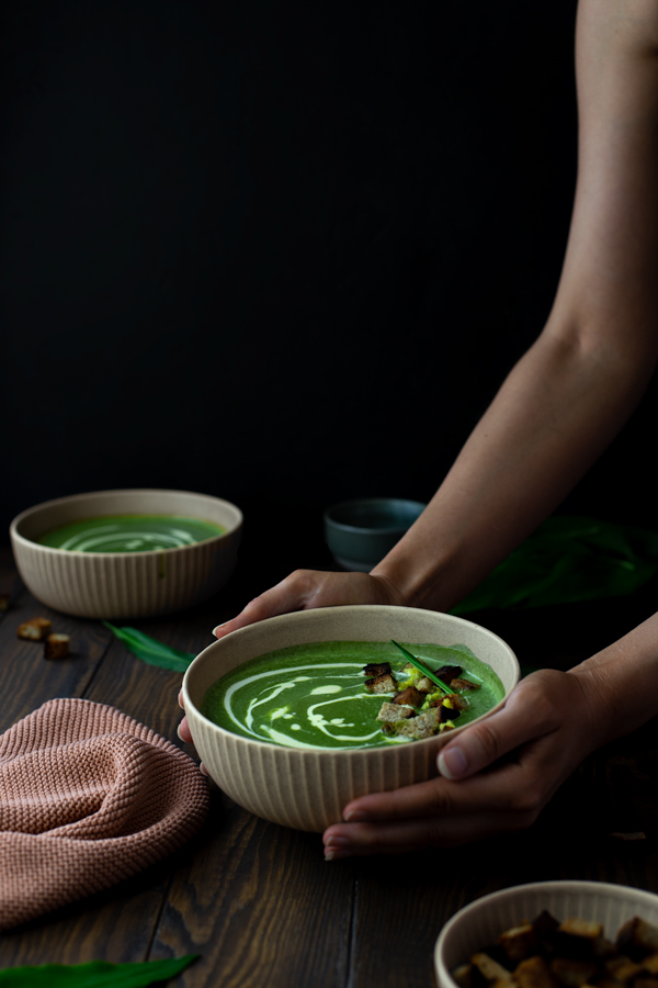 A woman holding a bowl of vegan coconut wild garlic soup