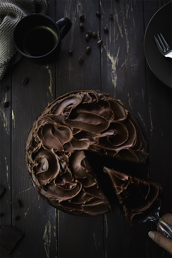 Ein Stück veganen Schokoladenkuchen mit einer Kuchengabel herausheben