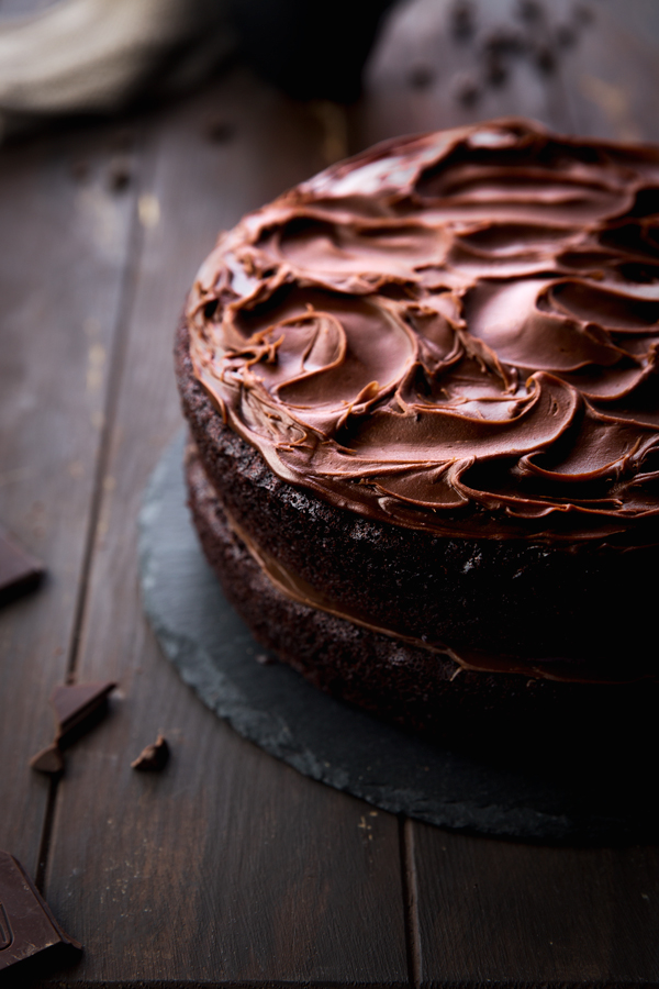 Vegan chocolate cake with chocolate frosting on a wooden surface