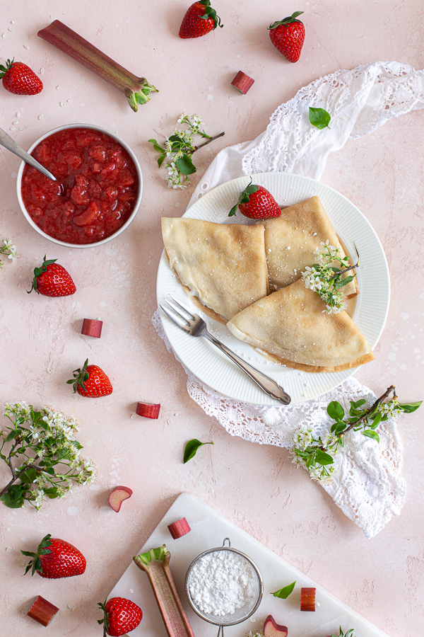 Vegan crêpes dusted with powdered sugar on a white plate