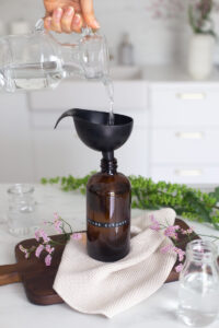Pouring vinegar into a brown glass bottle to make a DIY glass cleaner