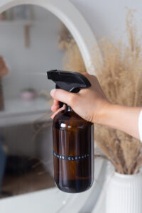Spraying the DIY glass cleaner onto a mirror