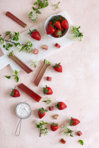 Ingredients for the strawberry rhubarb compote on a pink surface