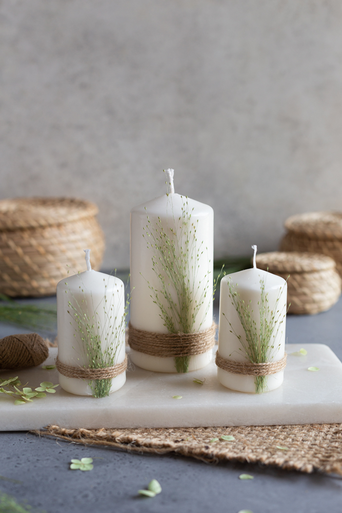 Drei DIY Kerzen mit gepressten Gräsern auf einem Mamorbrett