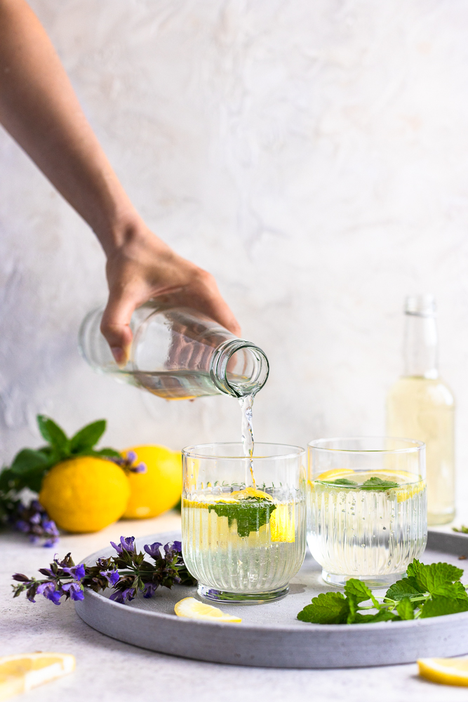 Pouring sparkling water onto lemon balm syrup