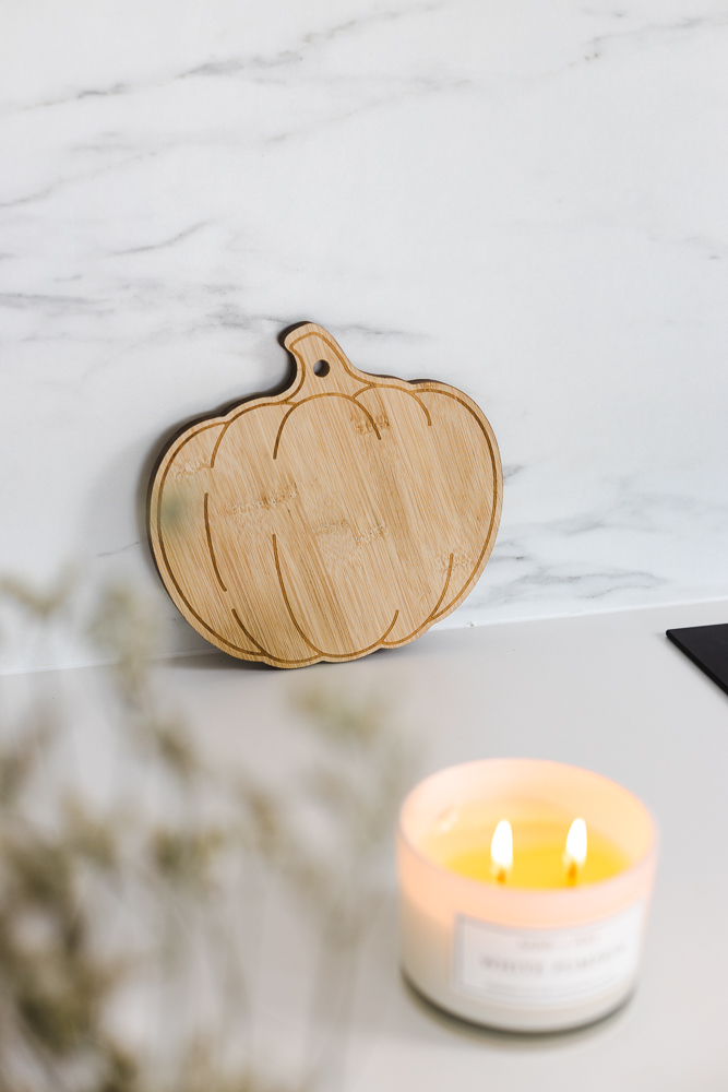Wooden pumpkin serving tray next to a candle