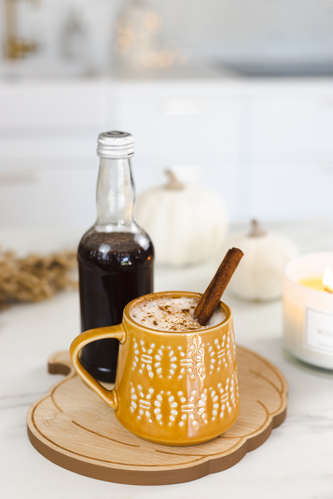 Homemade chai syrup next to a mug of coffee