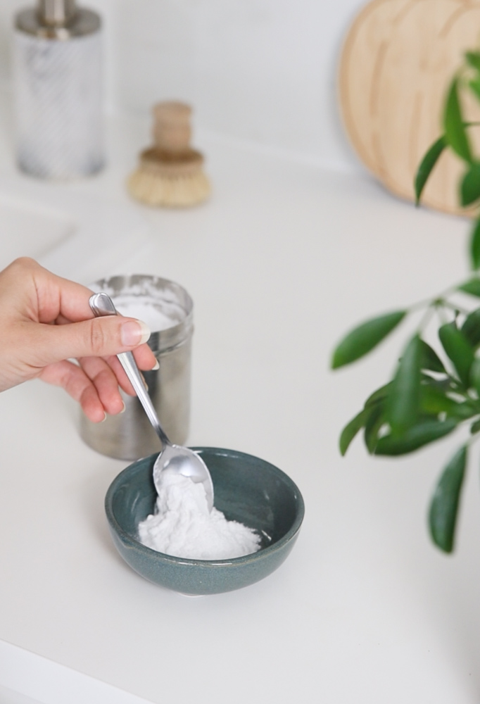 Adding baking soda to a dish for a DIY cleaning paste