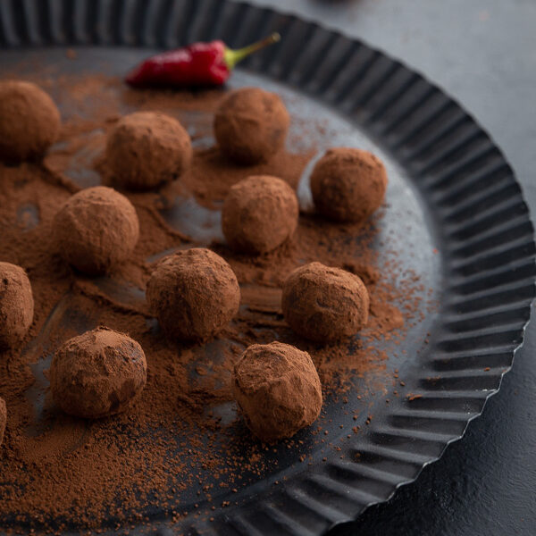 Spicy chili truffles rolled in cocoa powder on a black plate.