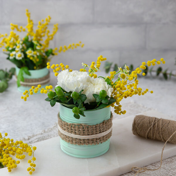 An upcycled green painted tin can with white and yellow flowers