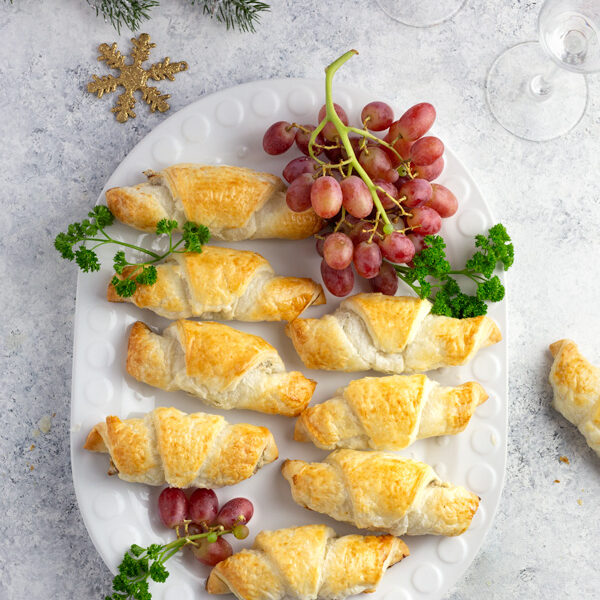 Goat cheese croissants with walnuts on tray, garnished with grapes and parsley