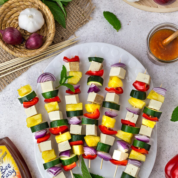 Raw veggie and tofu skewers on a white plate
