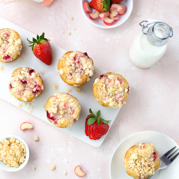 Strawberry Rhubarb Streusel Muffins on a pale pink background